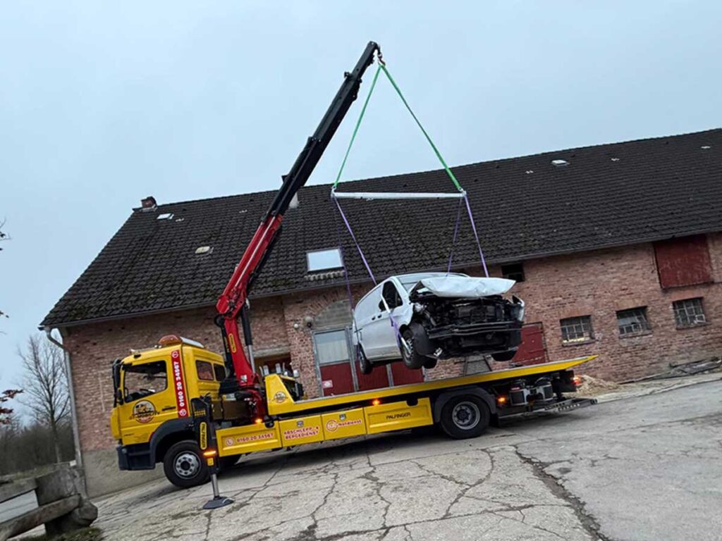 Abschleppdienst bei der Bergung eines Unfallautos mit Ladekran auf Abschleppwagen im 24h Notdienst